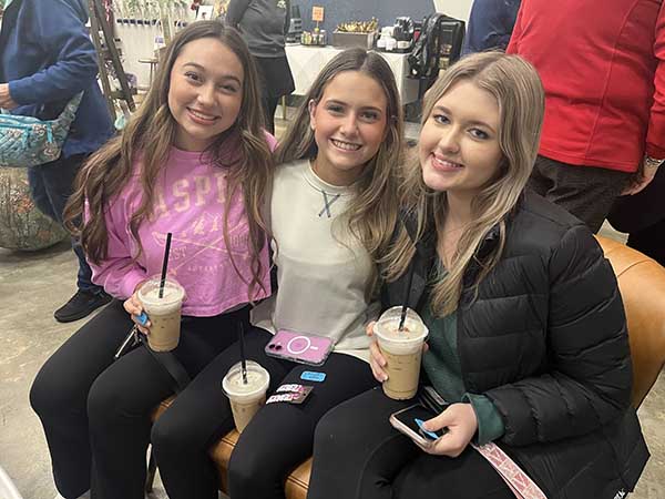 Group of ladies sitting together drinking iced coffee.