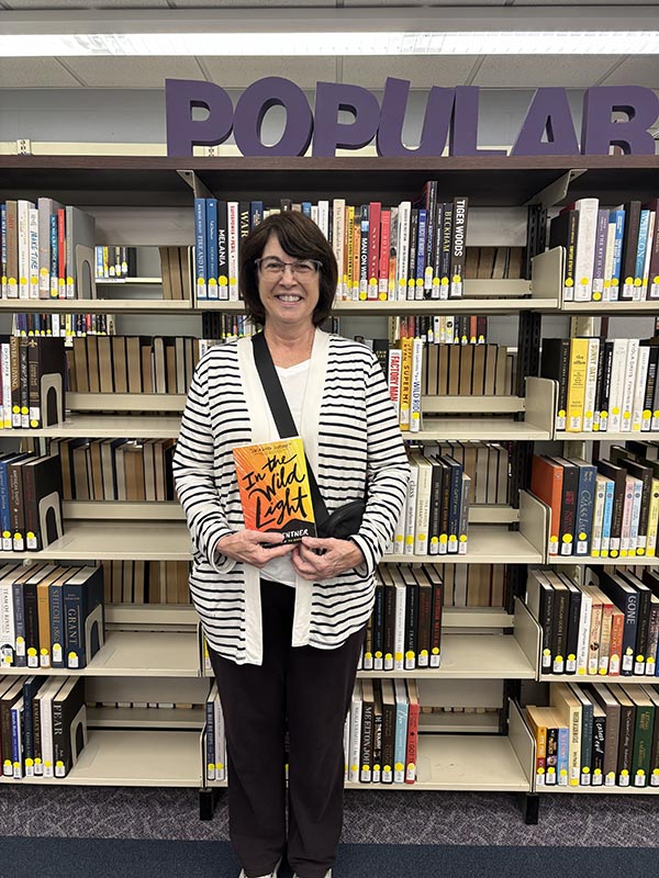 Lady in library holding a book In the wild light