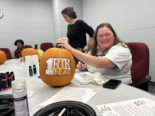 Lady painting a pumpkin reading 1book1read