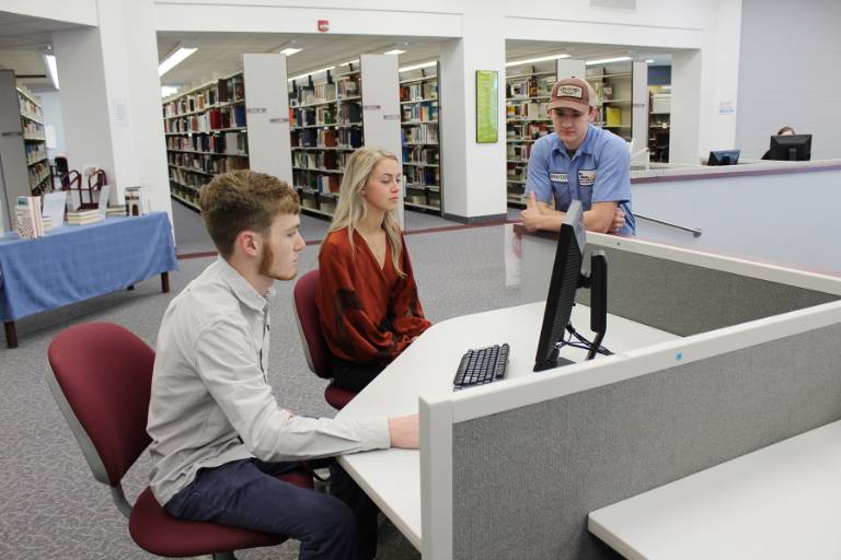 3 students in the library looking at a computer