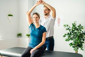 PTA helping a patient raise their arm above their head.